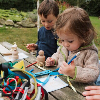 boy and girl decorating wooden peg dolls