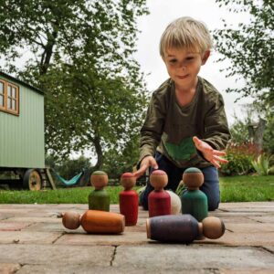 boy playing with wooden skittles game.