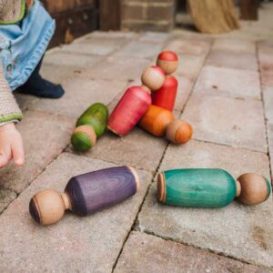 Girl playing with a colourful handmade wooden skittles game.