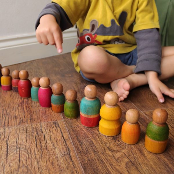 boy counting colourful peg dolls