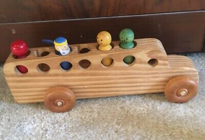 A wooden toy bus containing several wooden people figurines seated inside