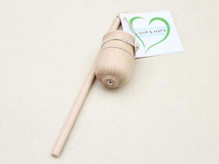 A wooden spoon featuring a tag, positioned on a neutral background