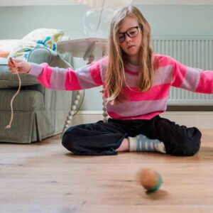 Girl using a wooden spinning top with string.