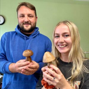 Two smiling DT teachers holding their turned mushrooms