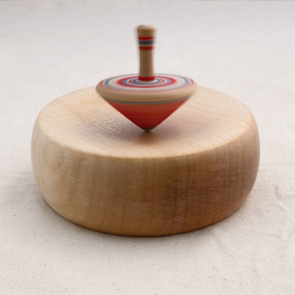 wooden spinning top spinning on a wooden base