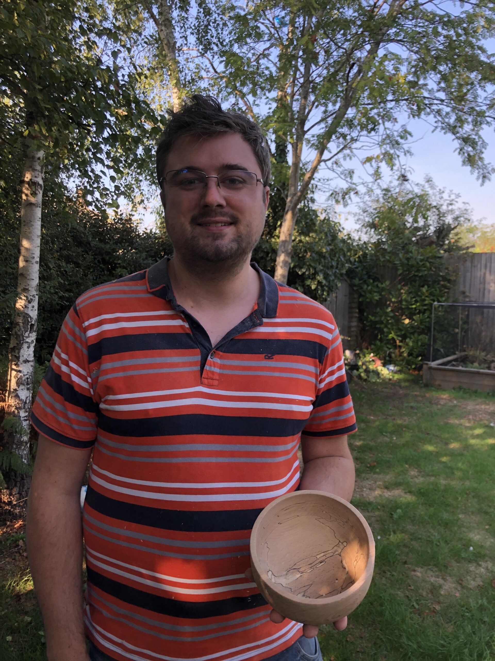 Man holding a wooden dish he made himself