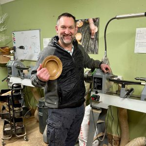 Private woodturning day student smiling and holding his bowl.