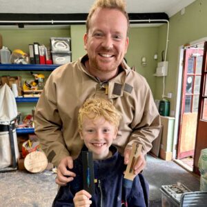 Smiling father and son holding handmade pens