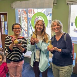 Three smiling students each holding their vases.