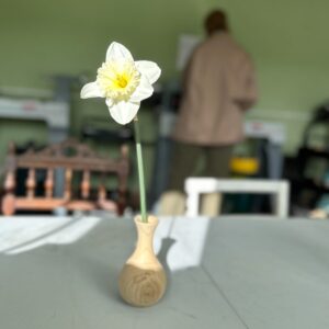 A wooden bud vase holding a daffodil.