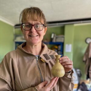 Woman holding the wooden vase she has made.