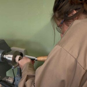 Woman hollowing out a wooden ring box on a lathe.