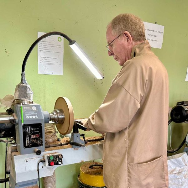 Man turning the outside of a wooden bowl on a lathe.