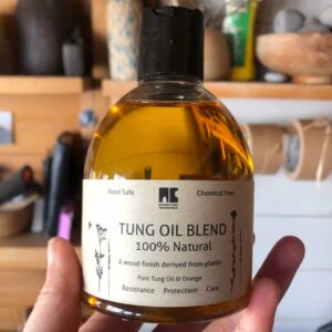 Hand holding a bottle of blended tung oil