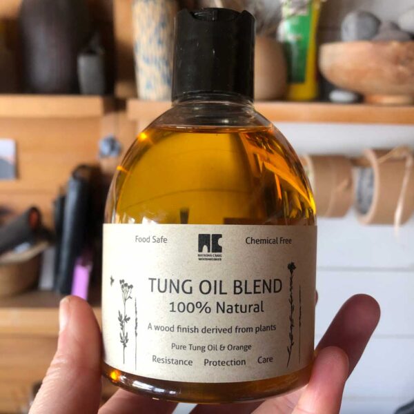 Hand holding a bottle of blended tung oil