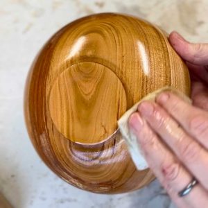 applying an oil finish to a turned cherry wood bowl