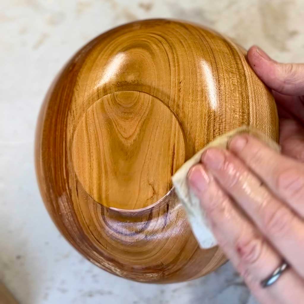applying an oil finish to a turned cherry wood bowl
