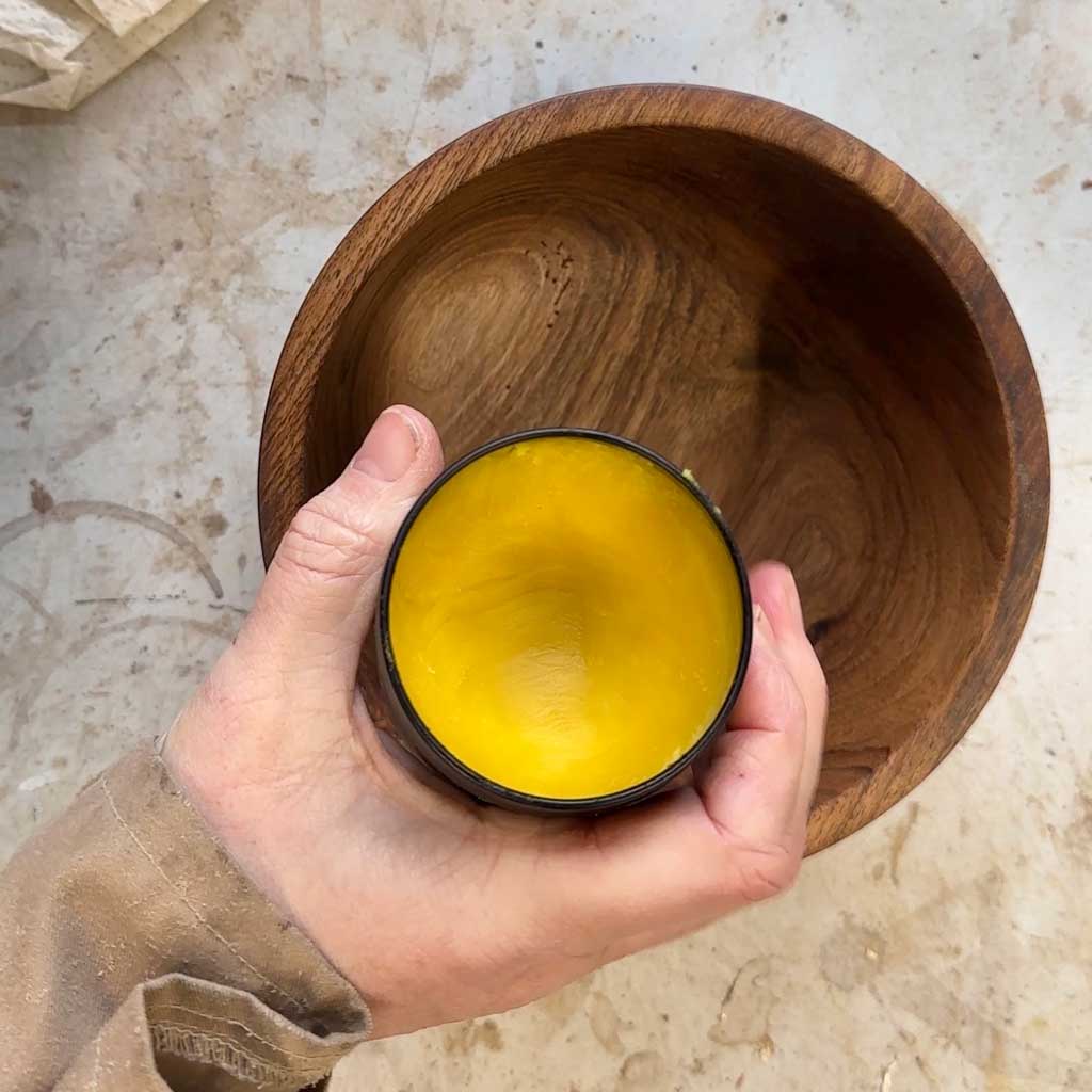 nc beeswax in a pot above a walnut wood bowl
