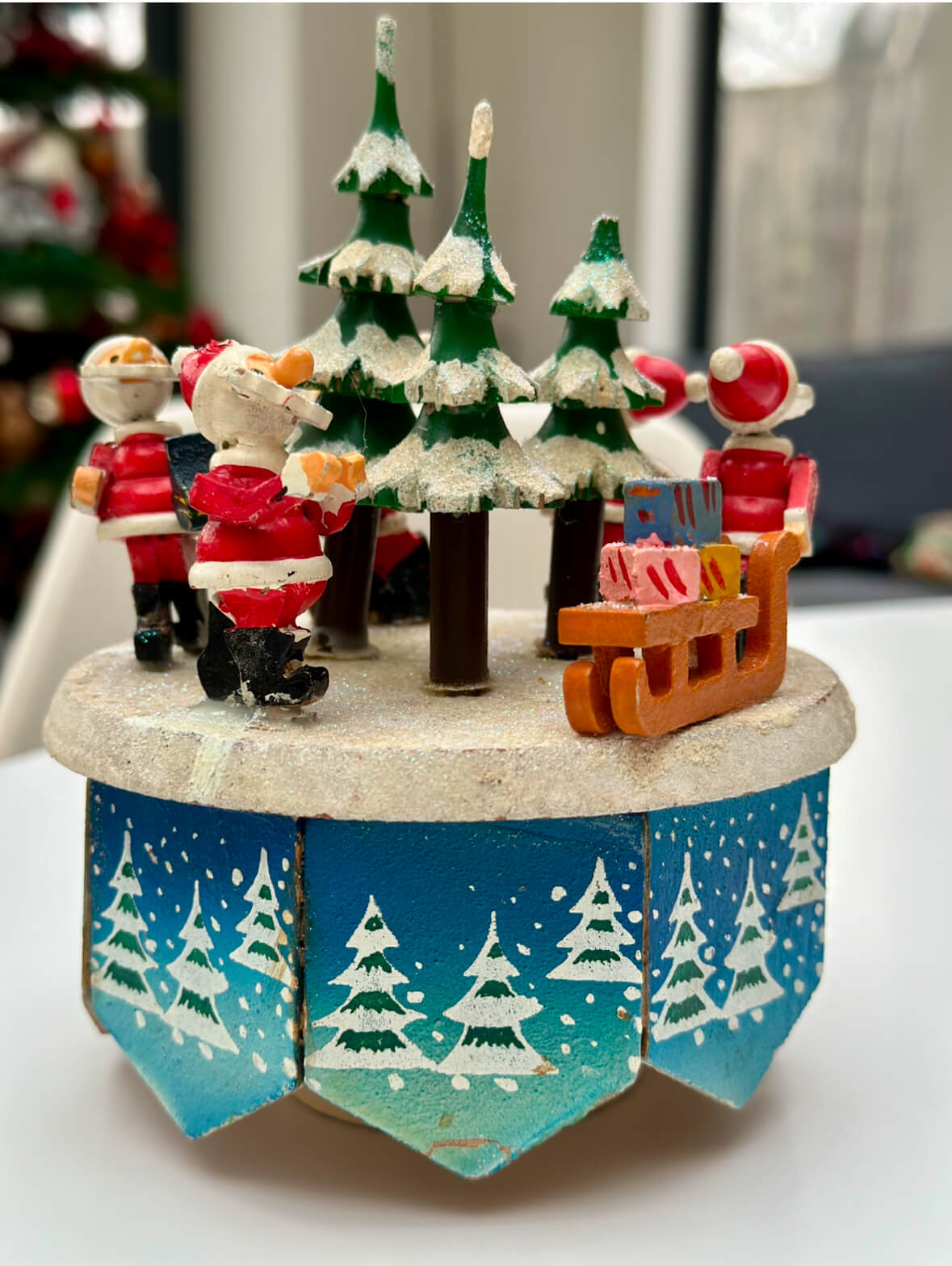 A small Christmas tree adorned with decorations, alongside Santa Claus and his sleigh in a festive setting