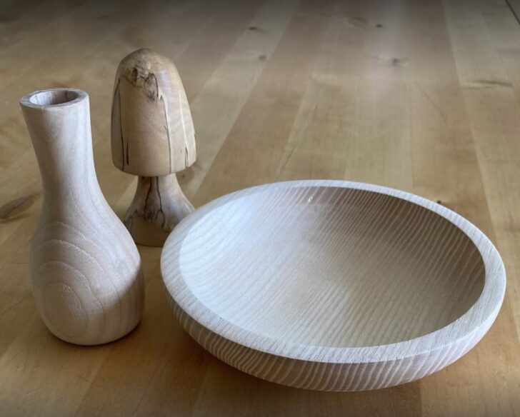 A wooden bowl and a wooden vase are placed elegantly on a table, showcasing natural textures and warm tones