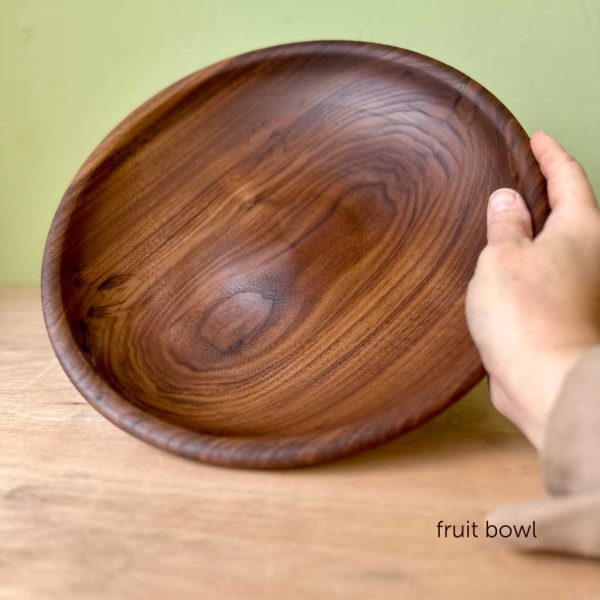 A hand holding an American walnut fruit bowl.