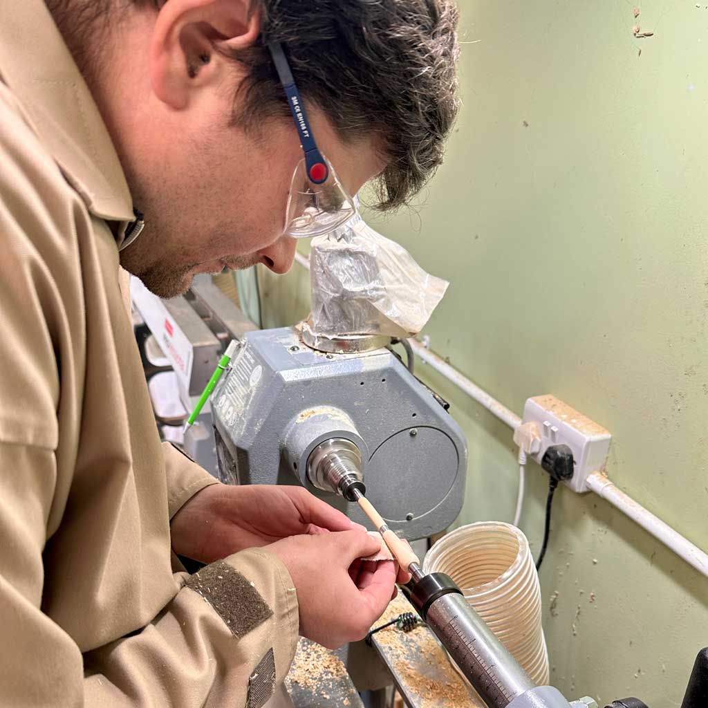 Man making a wooden pen on the lathe.