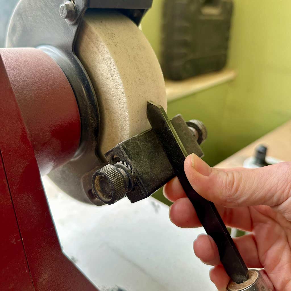 sharpen a parting tool on the grinder wheel using the table