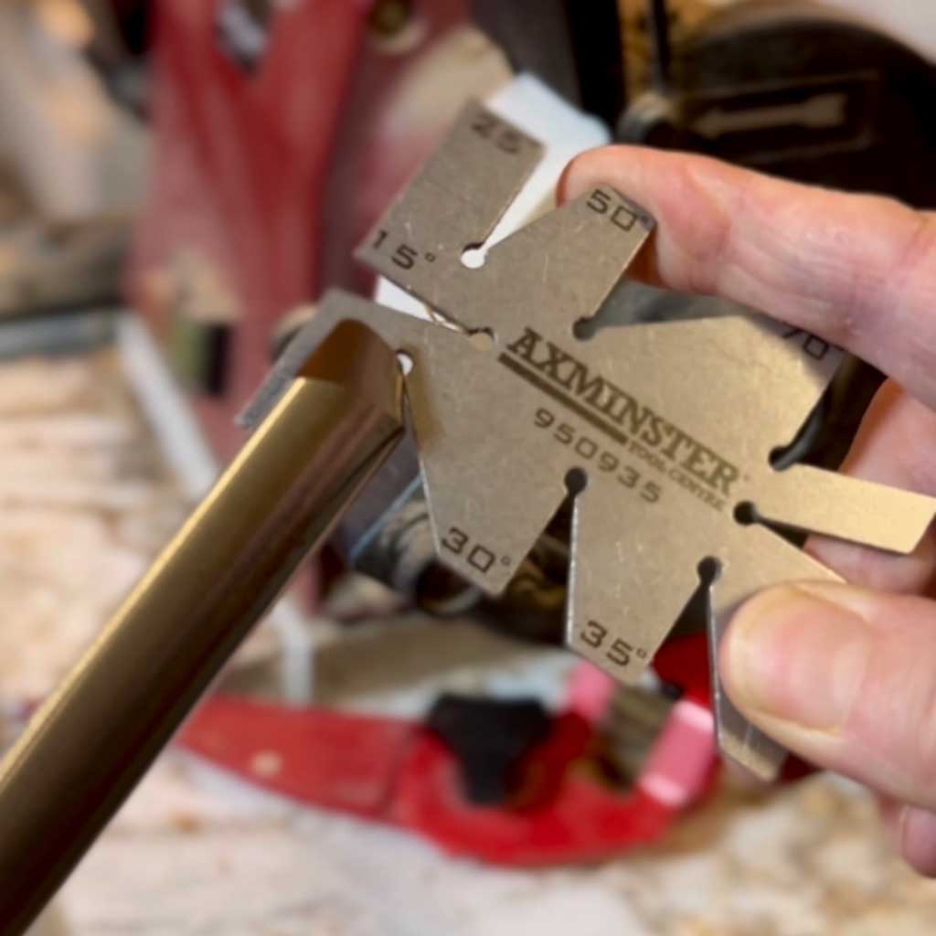 Using a metal angle checker to find the angle of a bowl gouge.