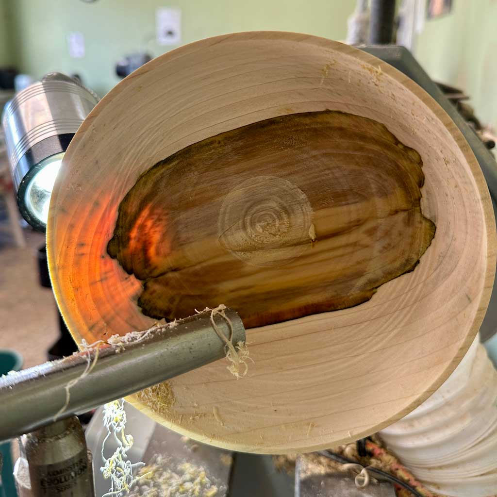 Close-up of the Rooted vessel being turned, revealing the natural rowan heartwood.
