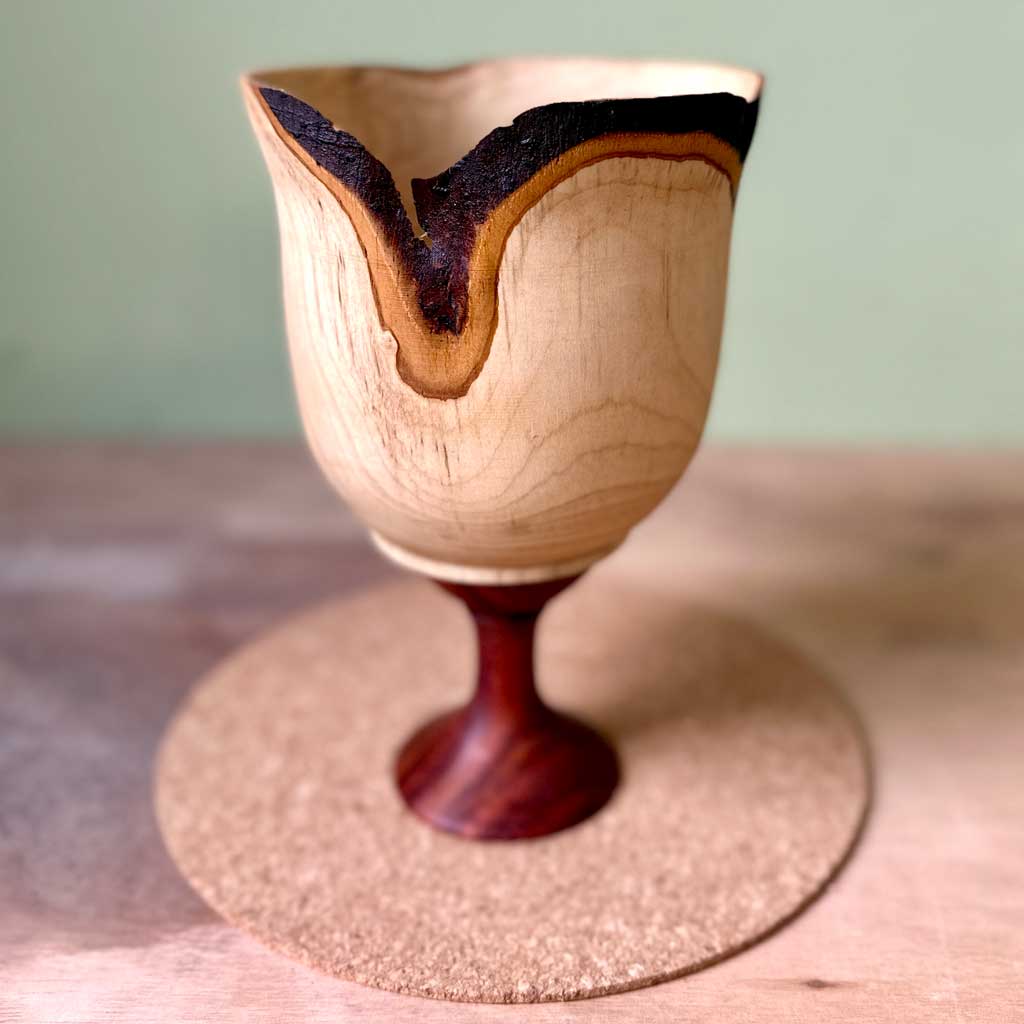 Unfolding hand turned green bay wood vessel with natural bark edge and flowing form.