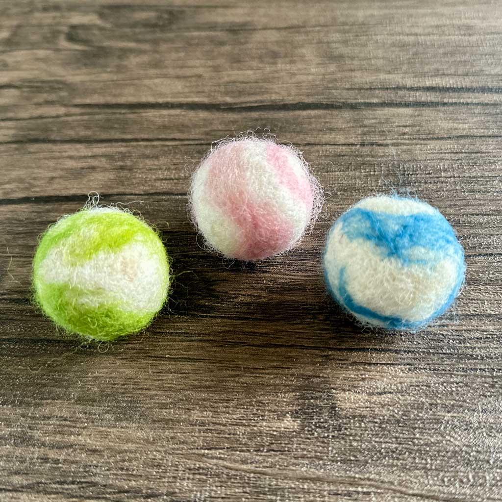 Three hand felted woollen balls in pink, blue and green.